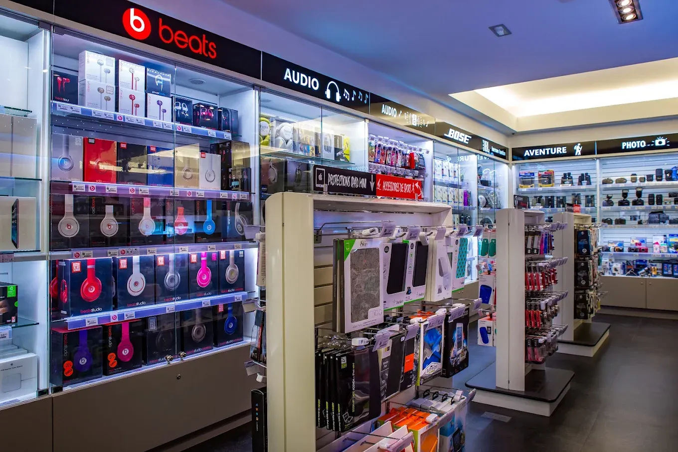 Mur de casques et d’écouteurs sous l’enseigne Beats, avec les protections de téléphone et les vitrines d’accessoires.