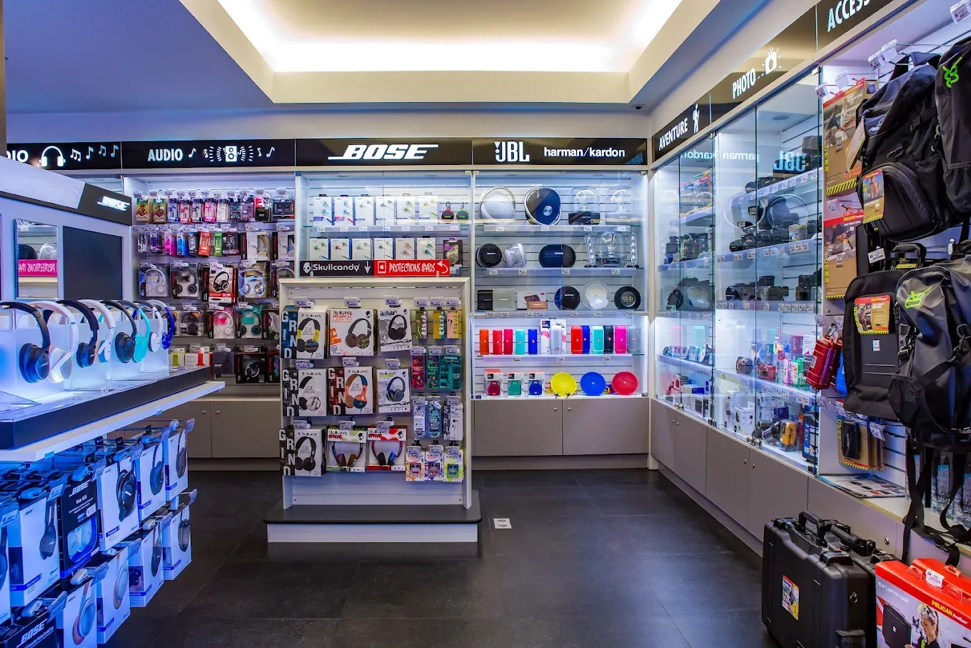 Vitrines d’enceintes portables sous les enseignes Bose, JBL et harman/kardon, avec les casques et les accessoires photo.