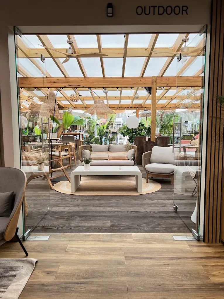 Mobilier d’extérieur sous une pergola en bois : canapé de jardin, fauteuils en teck et table basse, ouverts sur la végétation.