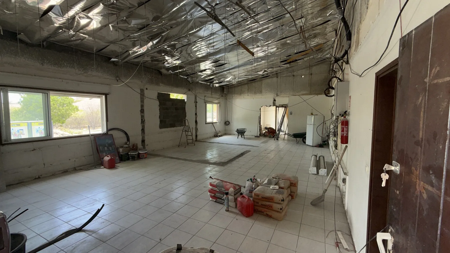 Le futur showroom de Mont Vernon en travaux : plateau dégagé, isolant au plafond, sacs de mortier au sol et attentes électriques le long des murs.